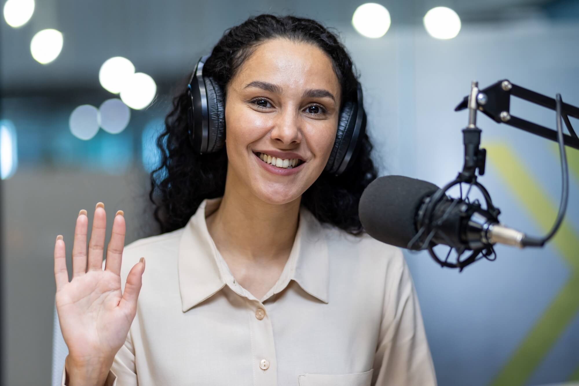 smiling-woman-with-headphones-waving-during-podcas-2024-08-02-14-54-52-utc.jpg